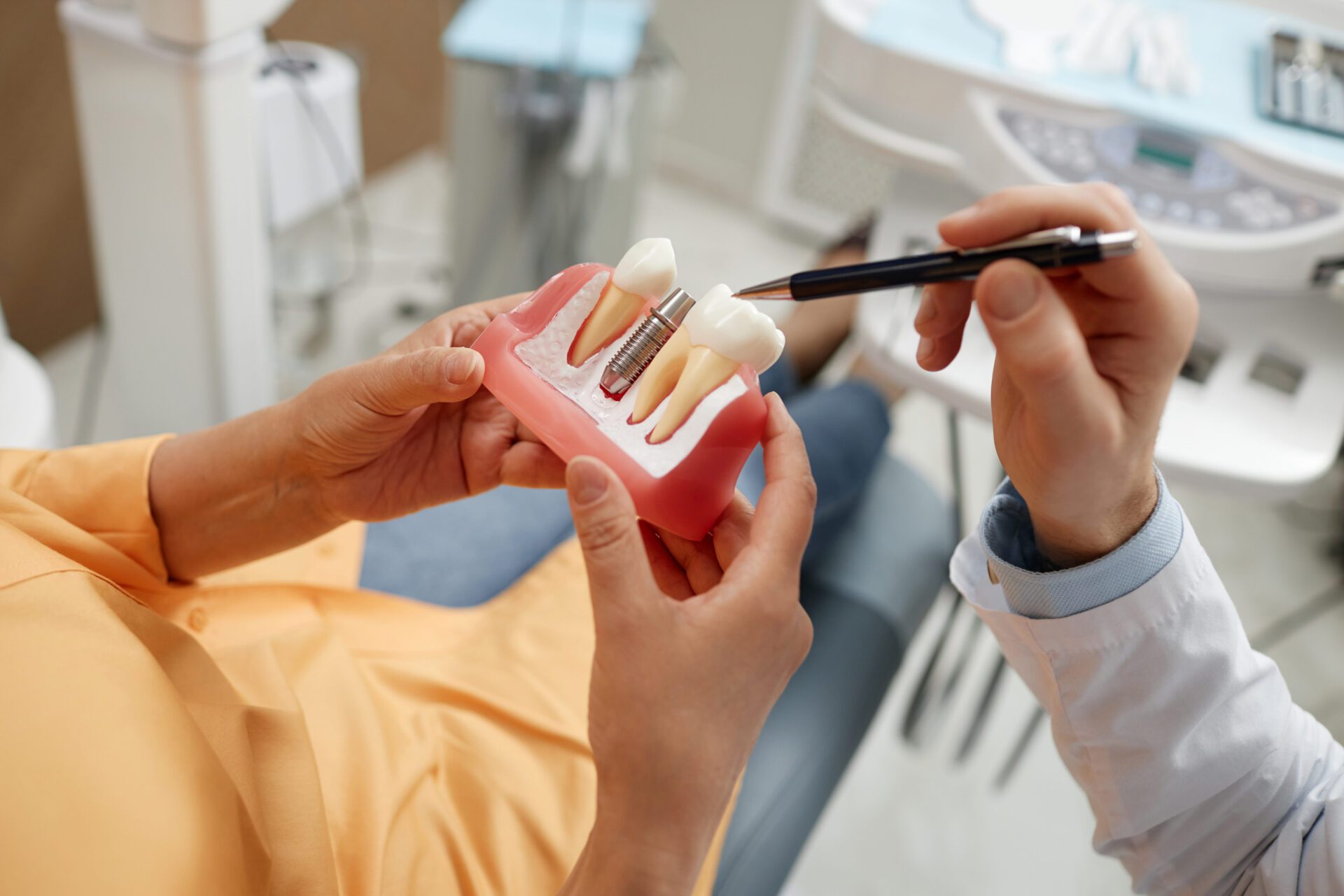 Woman holding tooth model during consultation on dental implant - Brandon, FL